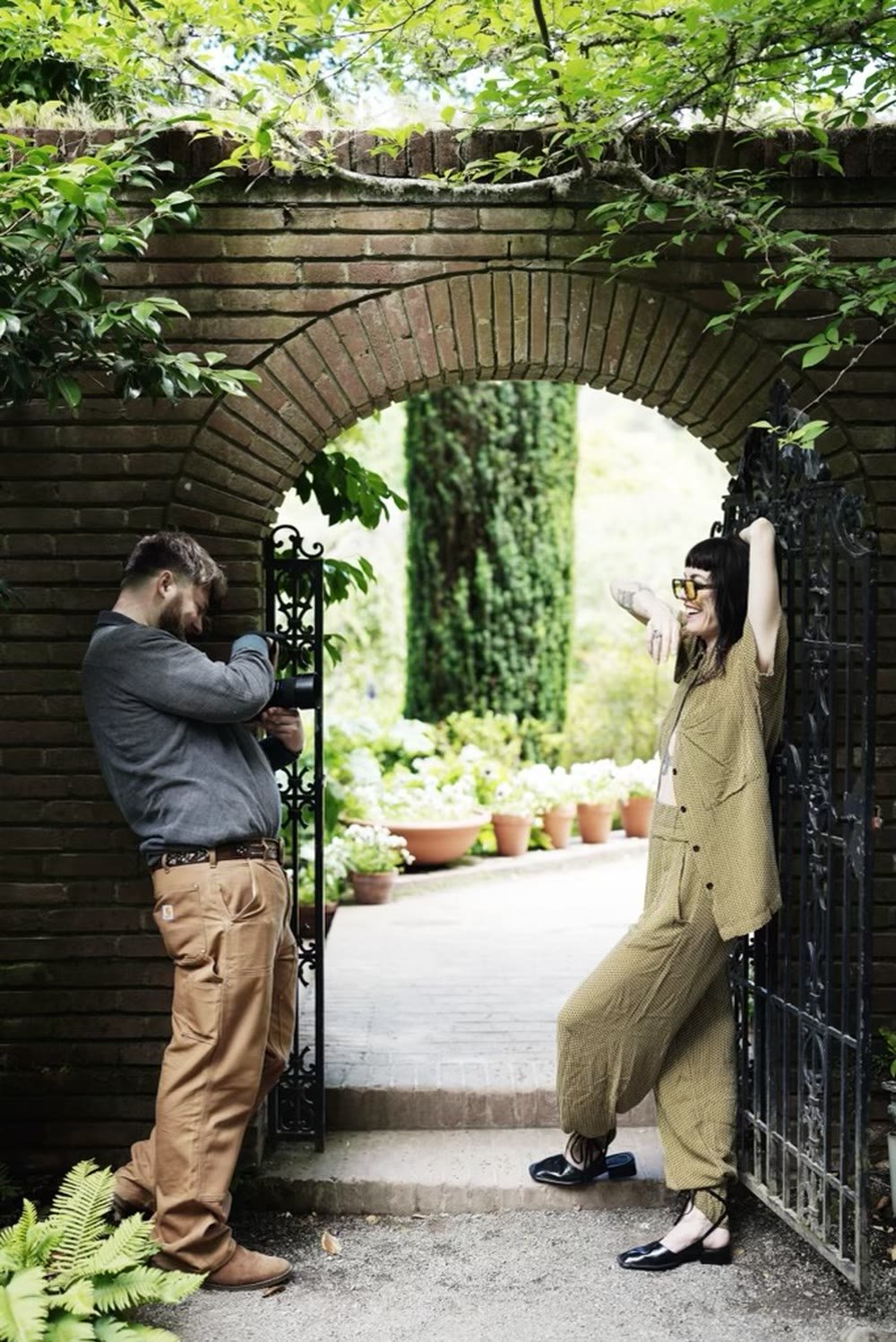 Photographer shooting a portrait subject beneath a brick garden arch